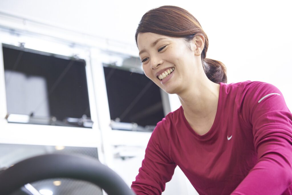 Disport World 六本木でバイクをこぐ女性の利用者