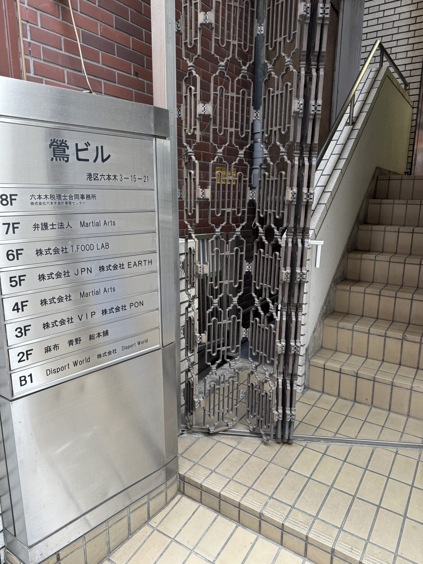 鶯ビルの館名板。B1にDisport Worldの表示